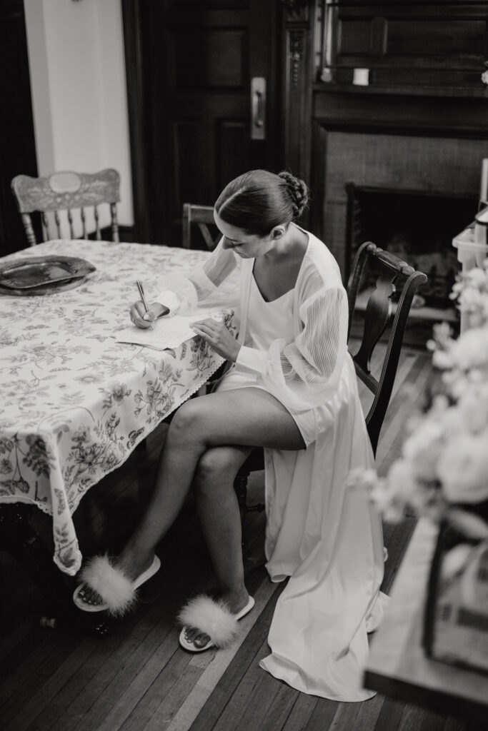 A black and white image of the bride hand writing her vows the morning of her wedding. 