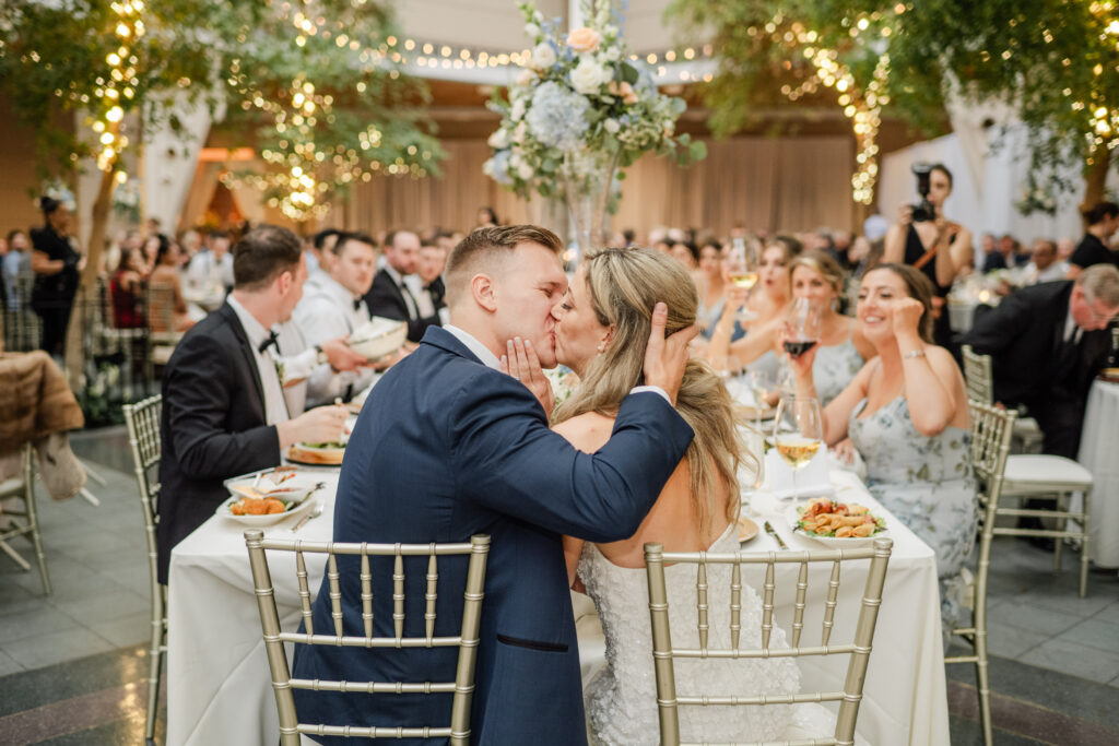 bride and groom kissing at captains table in the wintergarden wedding enue in rochester, ny