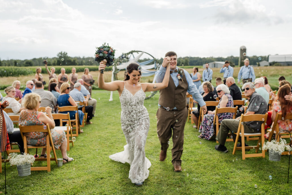 A bride and groom celebrating just getting married as they walk down the aisle together. 