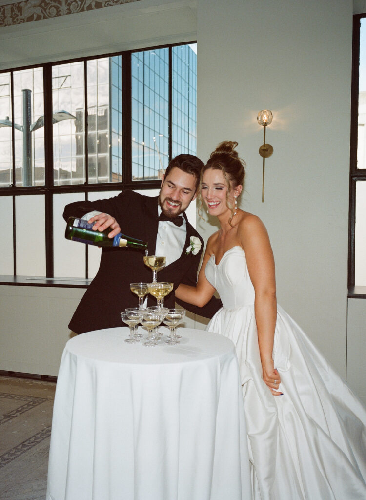 a 120mm photo of a bride and groom pouring over a champagne tower