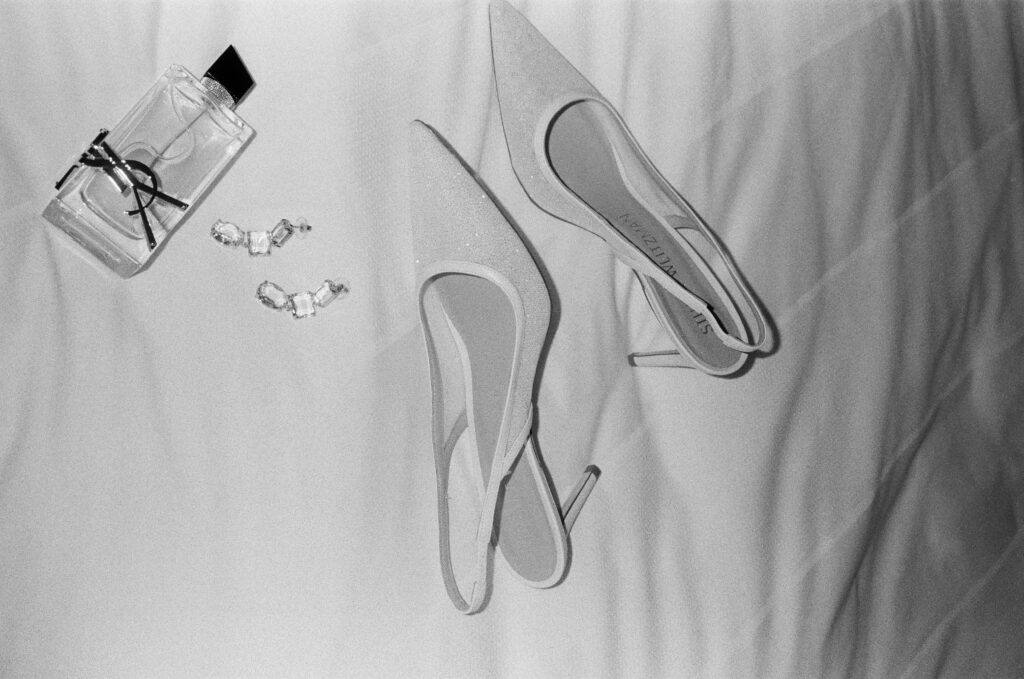 a wedding photo of shoes, perfume and earrings shot on 35mm film