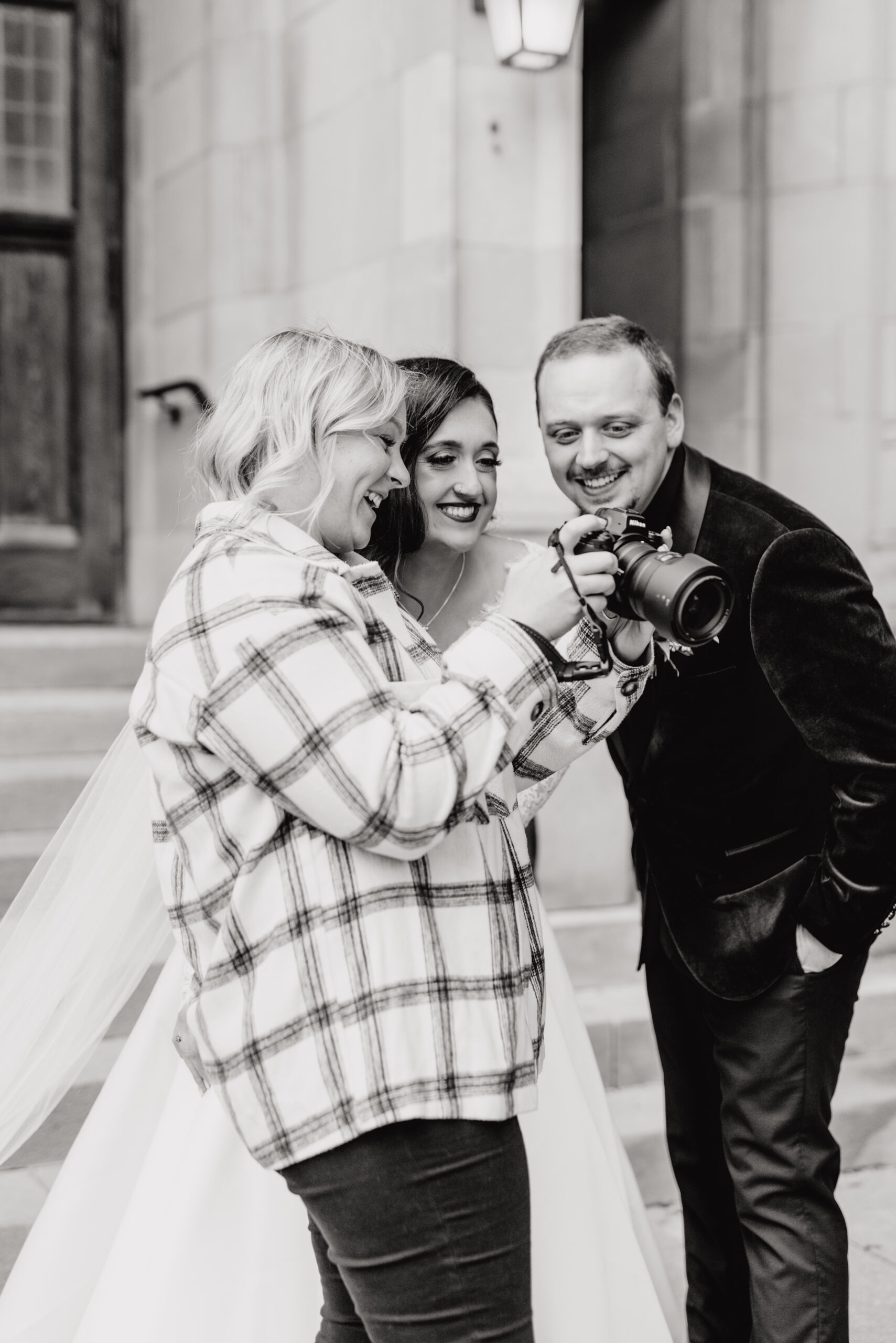 A couple reviewing a wedding photographer’s images on the back of their camera together.