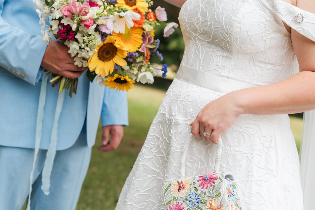 garden party wedding with colorful details, whimsical roadside stand wedding florals, colorful beaded purse and a light blue groom suit
