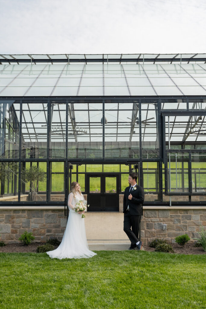 bride and groom pose for portrait within the greenhouse