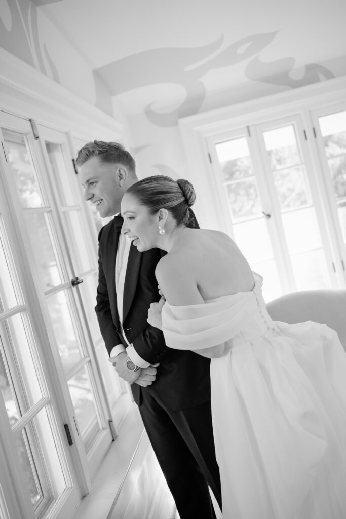 Documentary-style wedding photo of joyful bride and groom over looking their guests