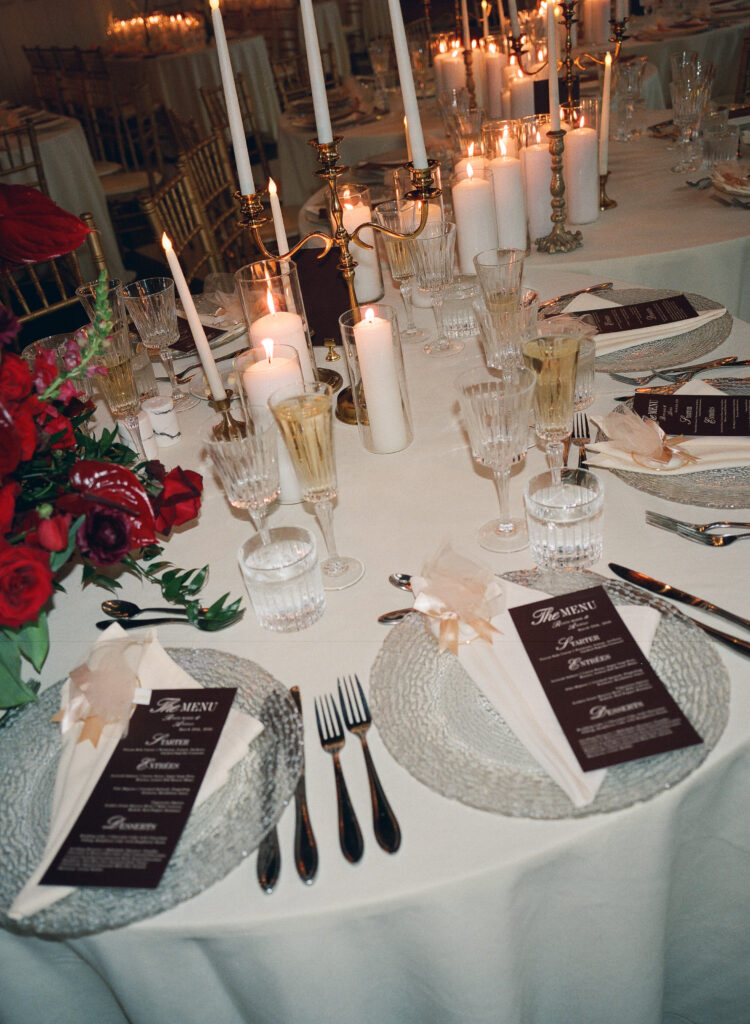 candles lit on reception table with red and white florals and candelabras 